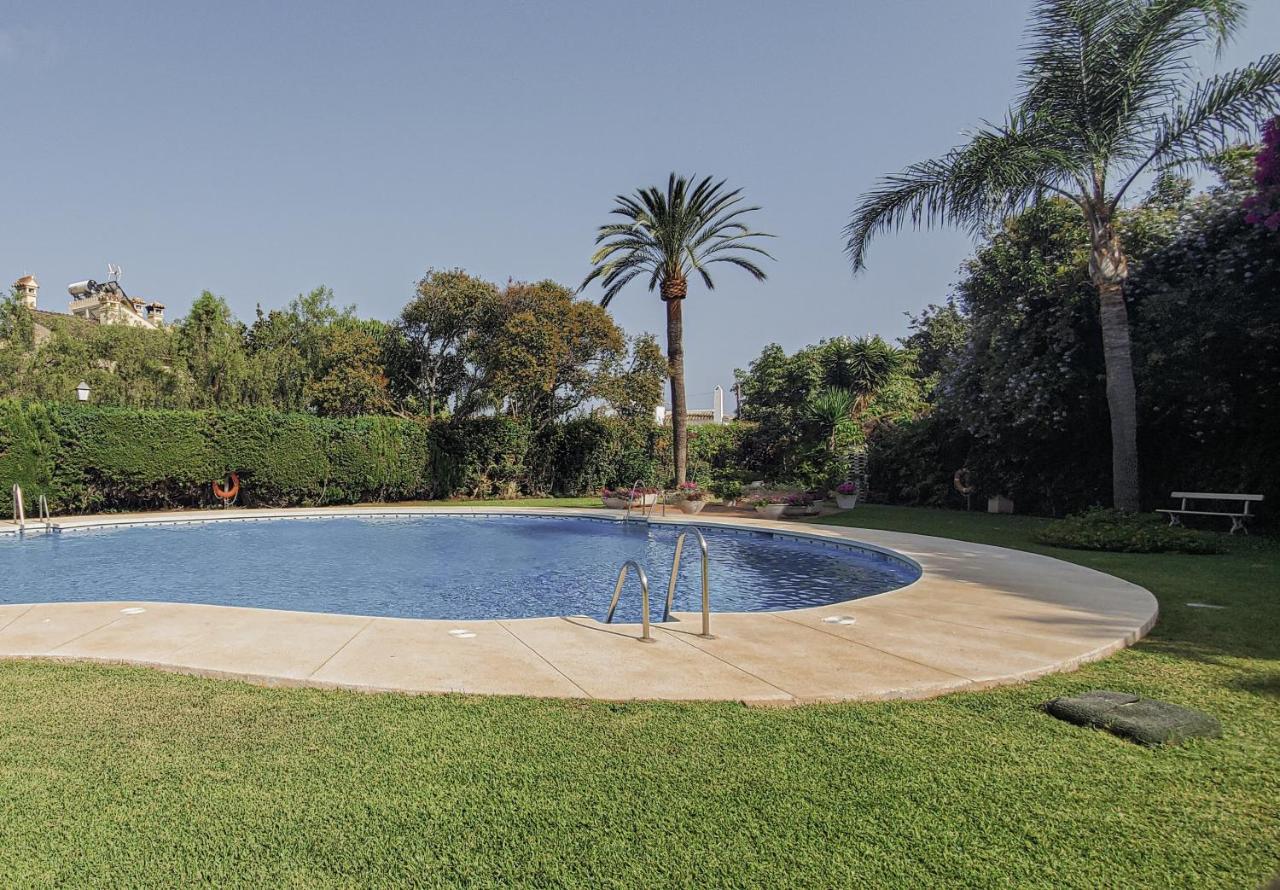 Piscina comunitaria con palmeras y jardín